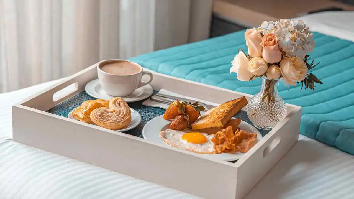 Desayuno en una charola en la cama de una habitación del Hotel Punto MX