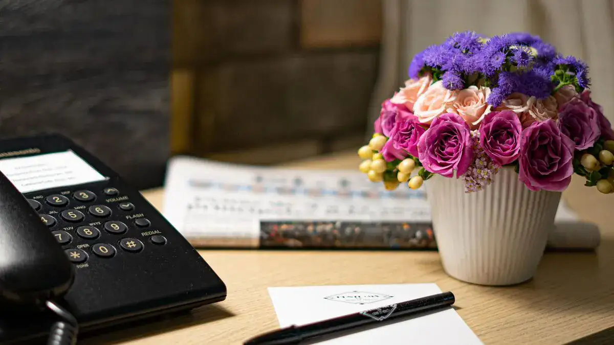 Bloc-notes et téléphone sur la table de nuit de la chambre à l'Hôtel Punto MX avec un journal.